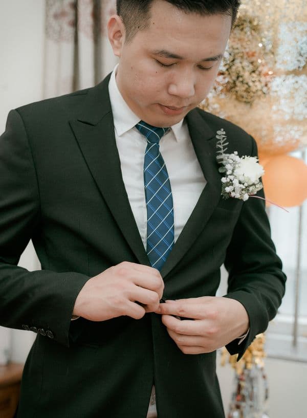 Man adjusting a black suit before a wedding ceremony