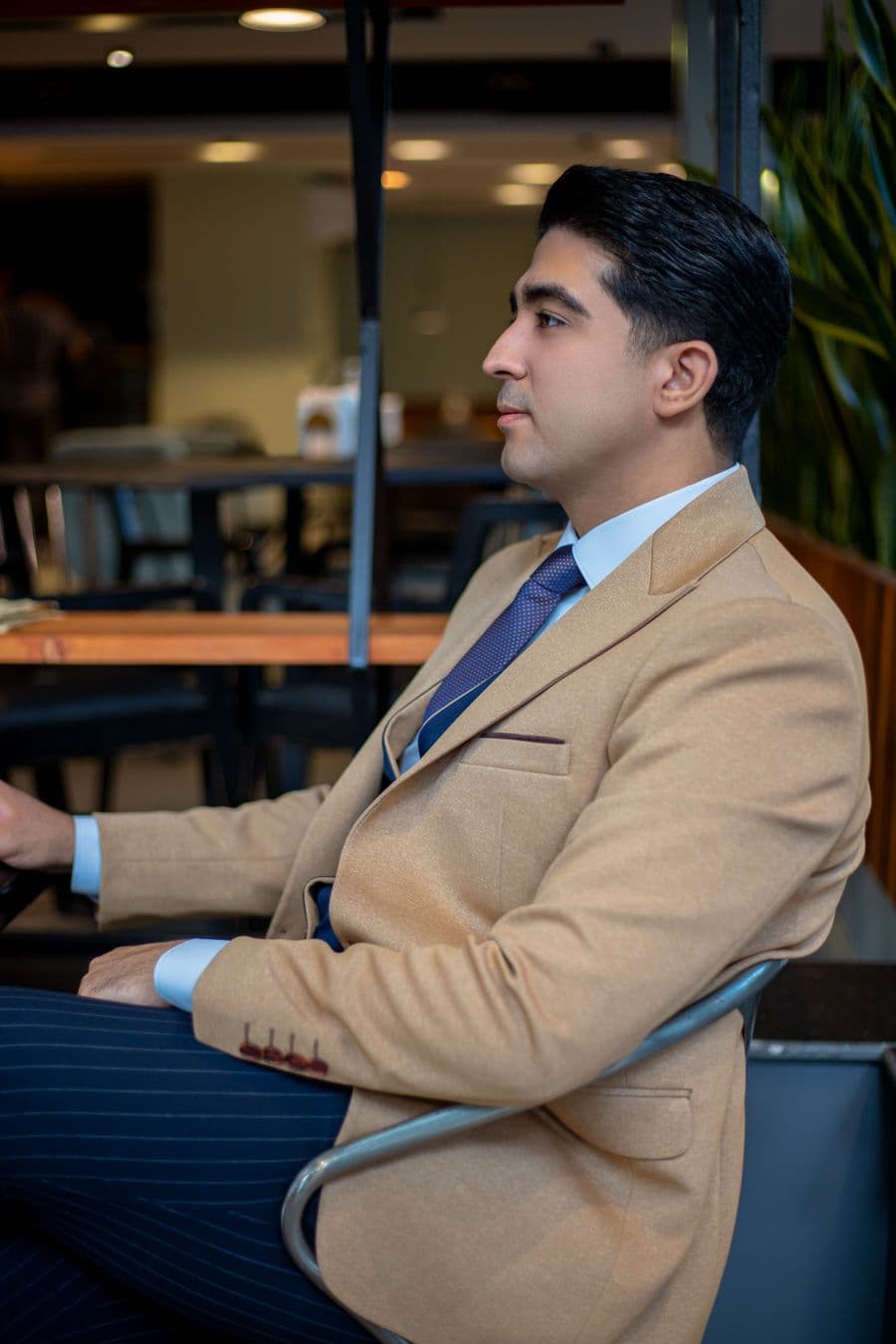 Man in a tan sport coat, light blue shirt and navy tie