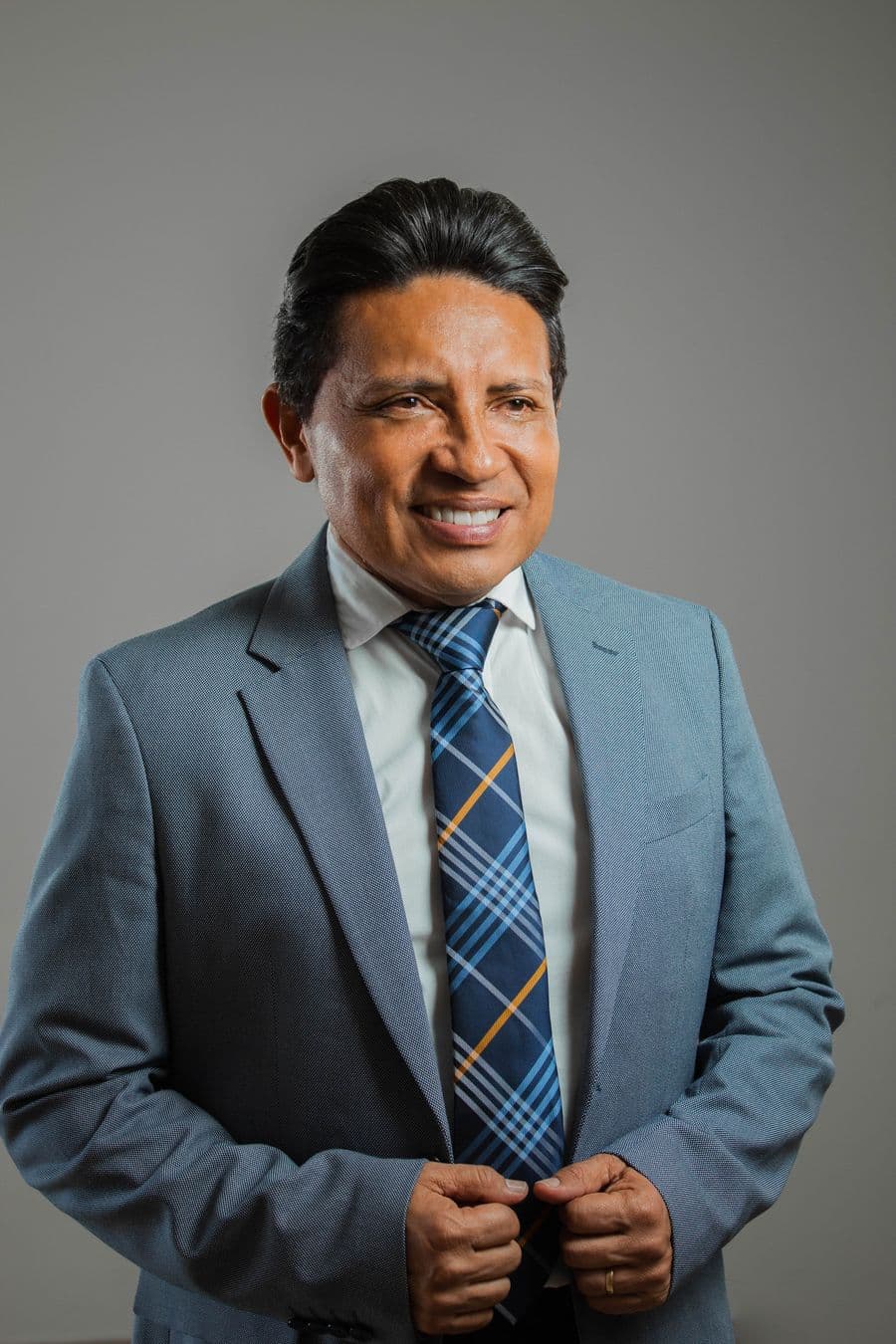 Man in a light grey-blue suit with a navy plaid tie