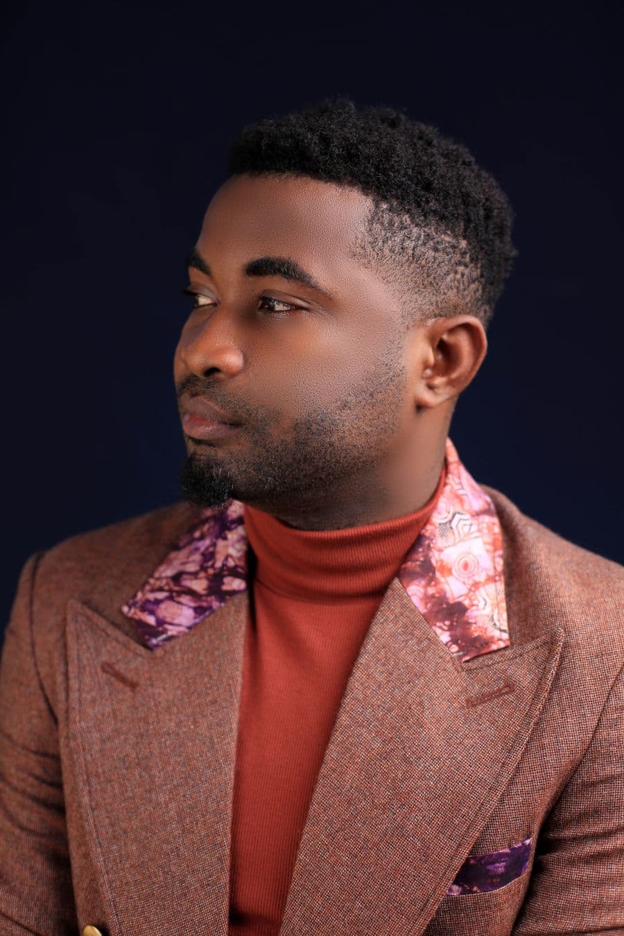 Man in a patterned blazer over a rust roll-neck